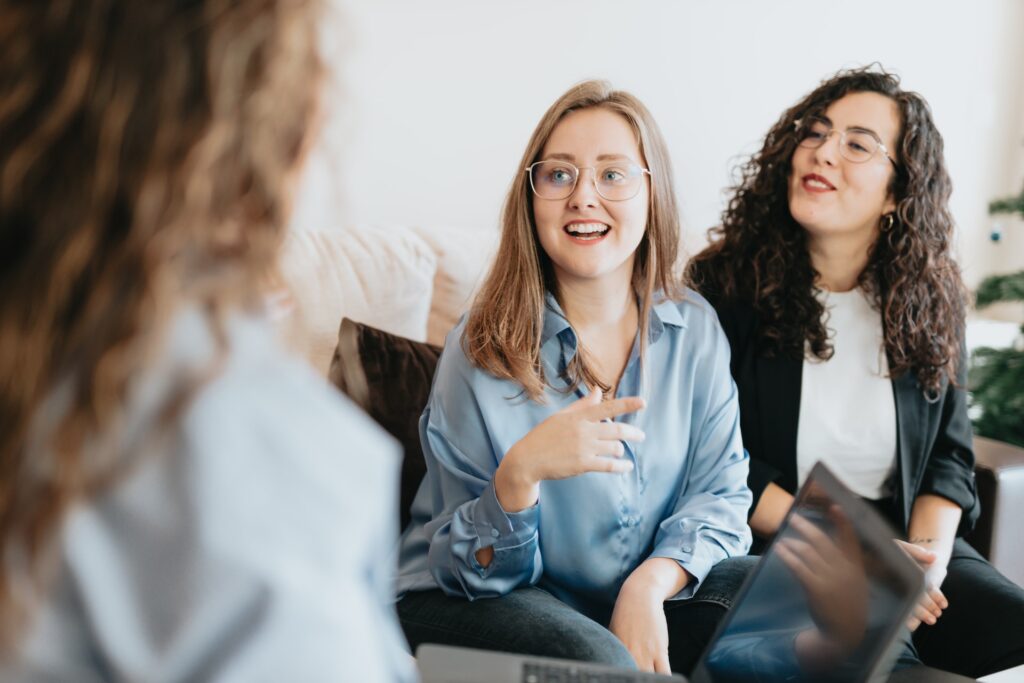 woman smiling very widely while chatting with a consultant on a couch